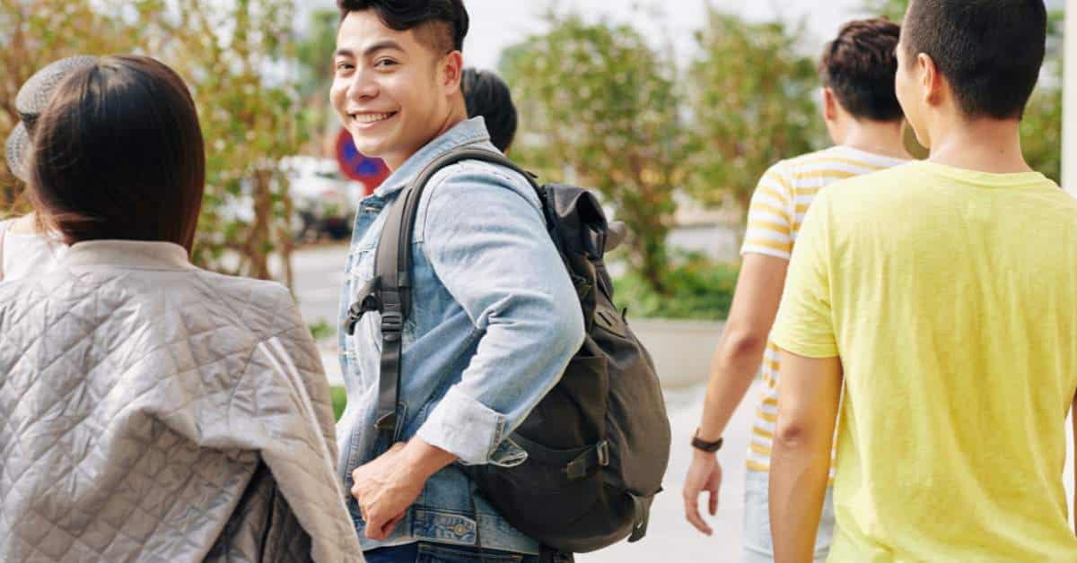 Teen walking on a college campus looking back at the camera