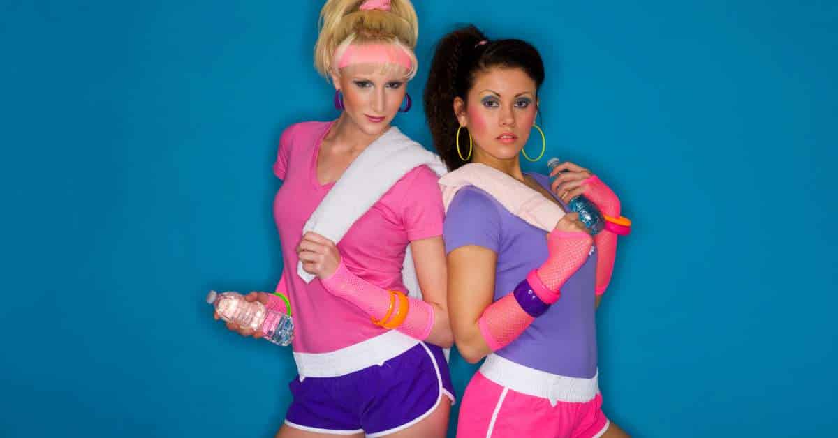 Two women wearing 1980s workout clothes with towels over their shoulders.