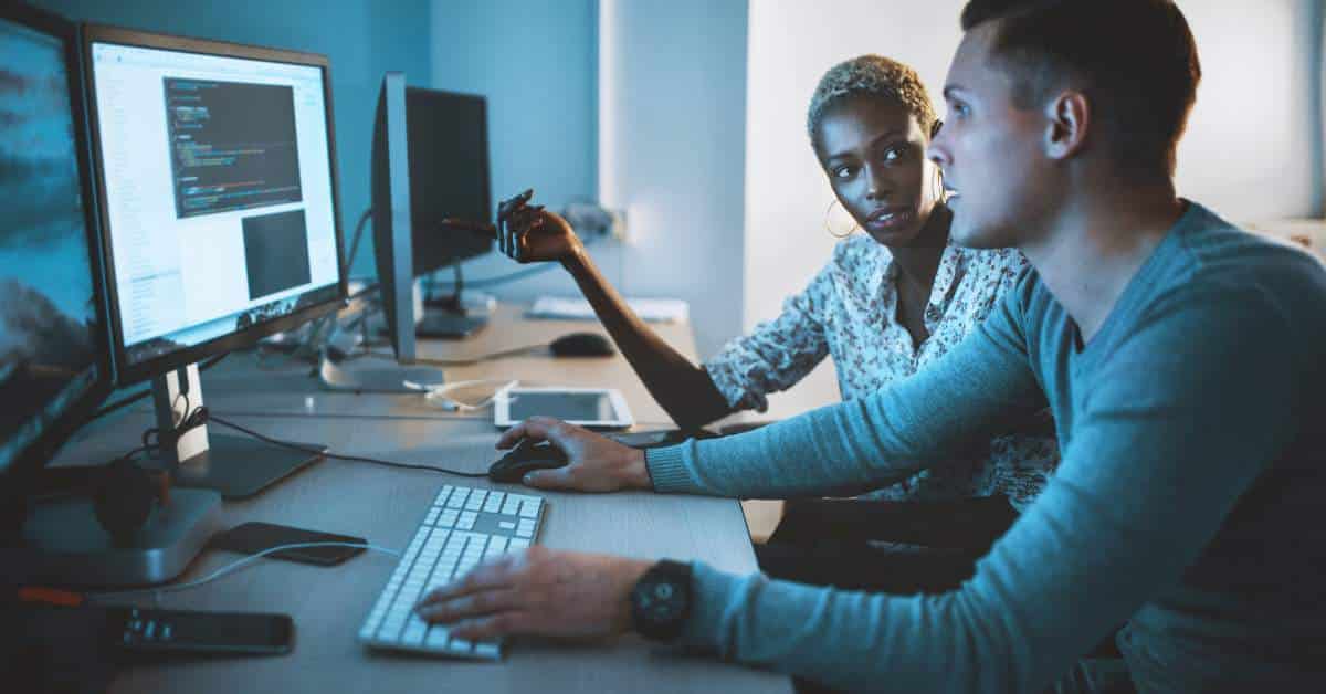 Mother and son sitting together looking at a computer screen while the son types on a keyboard