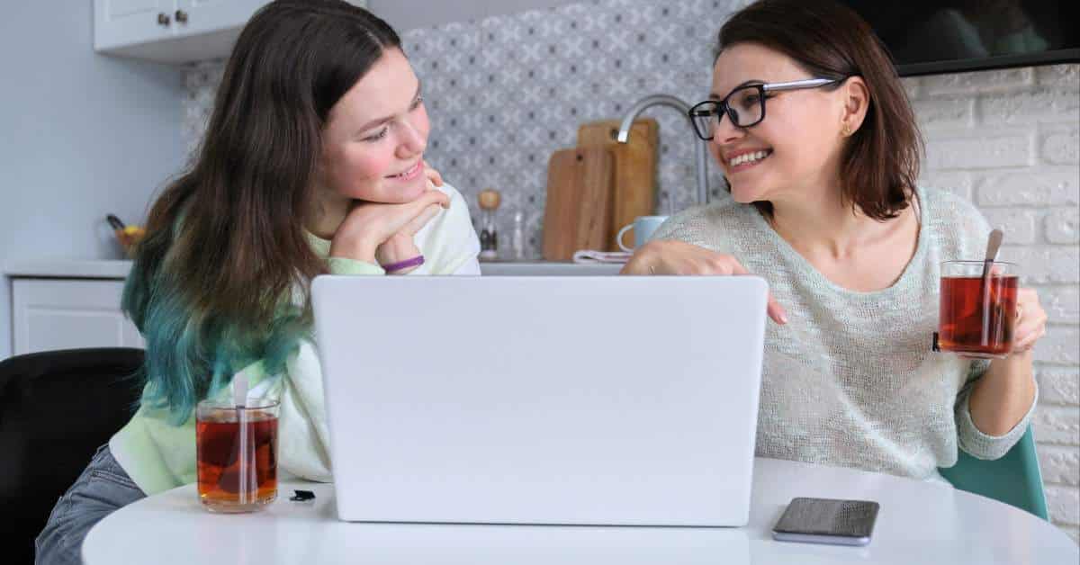 Mother and teen daughter having a discussion with a laptop in front of them.
