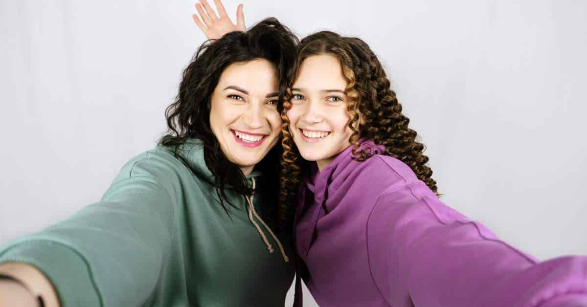 Mother and daughter head to head facing the camera and smiling.