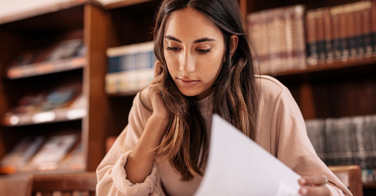 A young woman at a desk working and looking down at something.