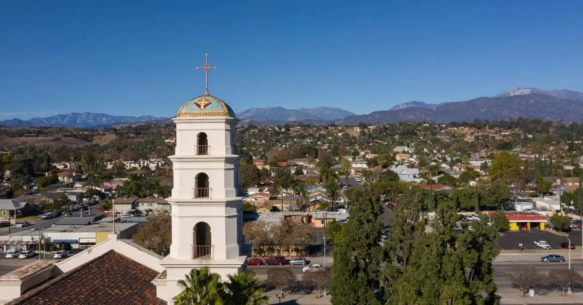 Large white tower in the foreground with the city of Pomona College behind it.