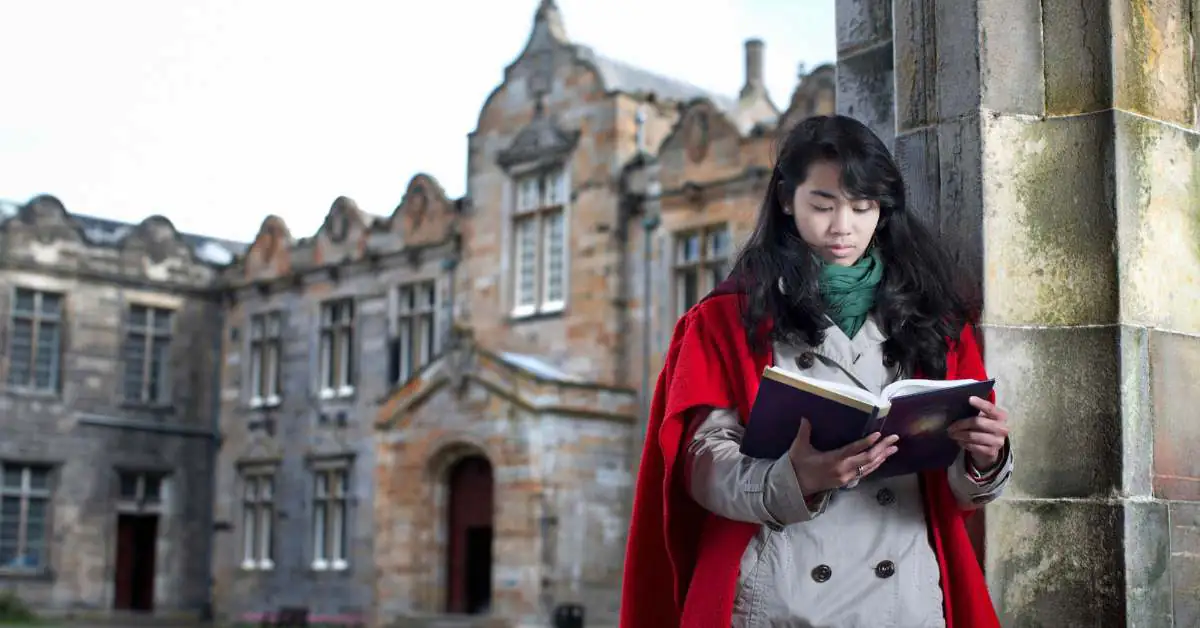Young woman wearing a red robe in front of a building at University of Saint Andrews
