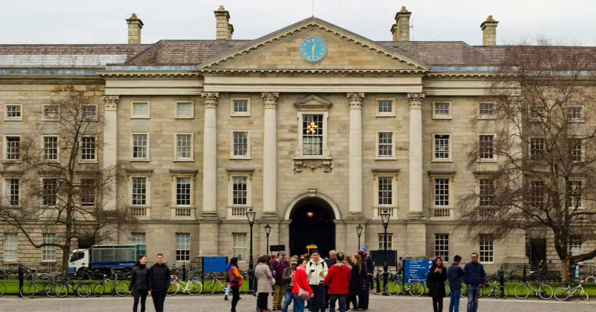 Large white building at Trinity College Dublin with students gathering in front.