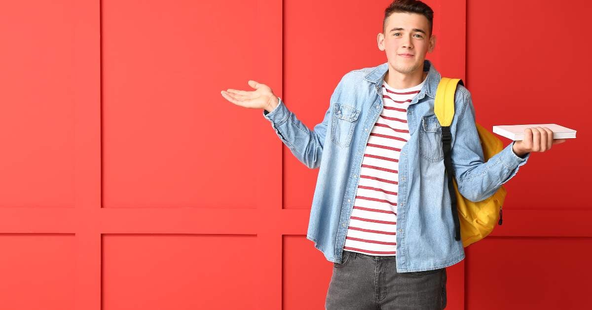 Teen boy facing the camera with his hands outstretched, palms up, looking confused.
