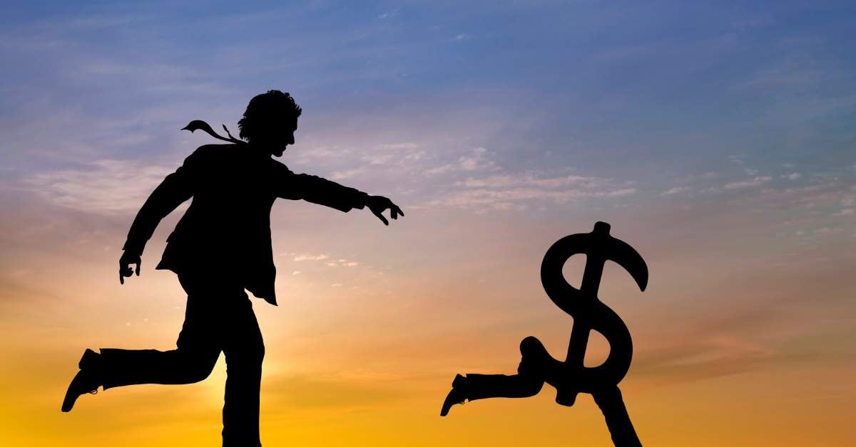 A sunset in the background. In the foreground, shadows of a man chasing a dollar signs with legs running away.