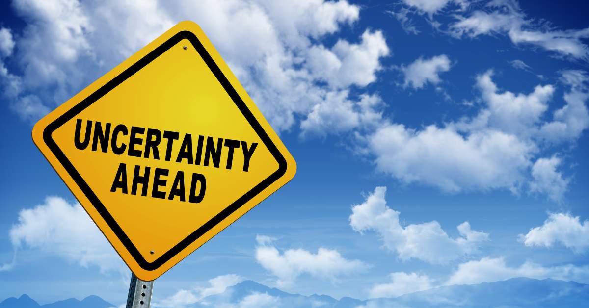Picture of a cloudy sky with a yellow road sign that says, "Uncertainty Ahead."