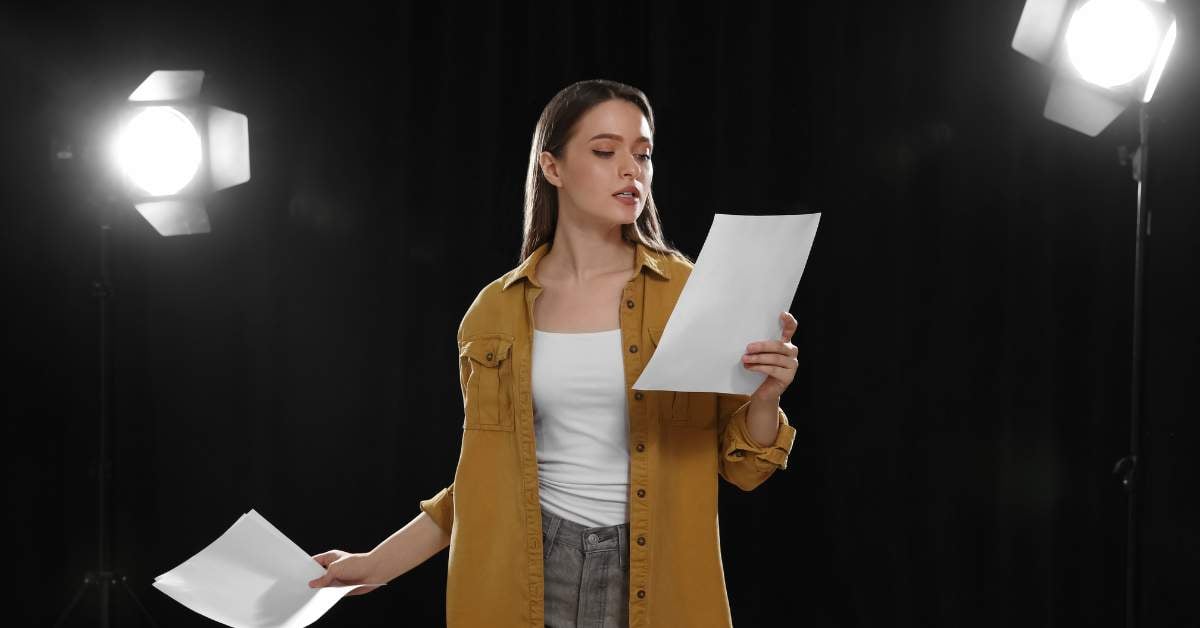 Young woman is on a stage, holding a script in her hand, delivering a monologue