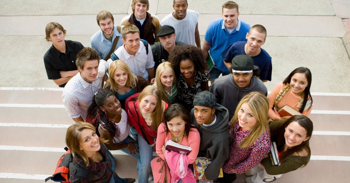 A group of students standing on white steps looking up at the camera